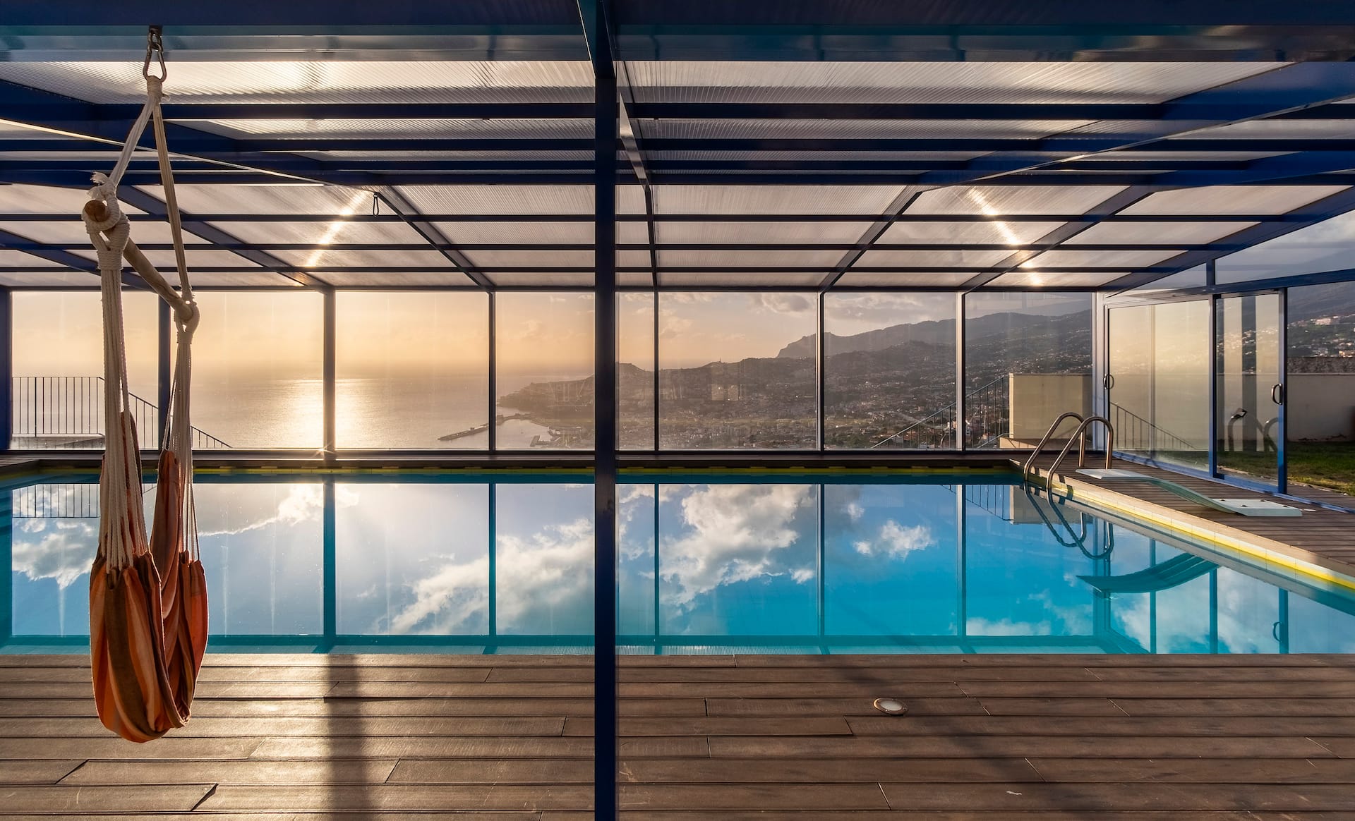 An infinity pool and lounge looking out over the coast at golden hour